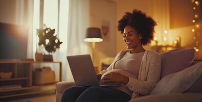 A pregnant woman is sitting on a comfortable sofa in a softly lit living room, happily using her laptop. It is evening, and warm light filters through the windows, creating a cozy atmosphere. photo