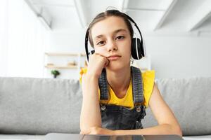 Upset Young Pupil In Headset Sitting At Desk Using Laptop Computer At Home, Tired Adolescent Having Problems With Online Education, Suffering Difficulties With Distance Learning, Webcam View photo