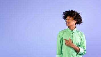Look at this. Excited african american student guy pointing and looking aside at empty space, standing over blue background, studio shot, copy space. Cool offer concept photo