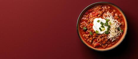 A bowl of hearty chili topped with sour cream and cheese. photo