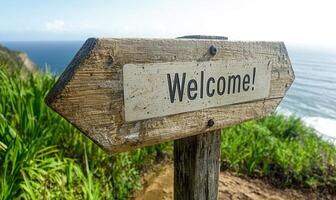 Wooden signpost with welcome message on a cliff overlooking the ocean photo