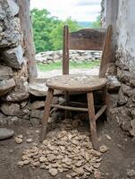Old wooden chair in a dilapidated stone building with scattered clay objects on the floor photo