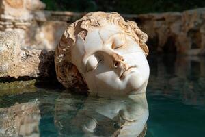 Submerged ancient statue head in a pool of clear water photo