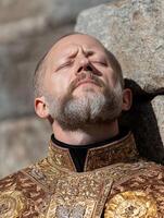 Man in ornate gold religious robe with eyes closed photo