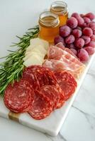 Charcuterie board with salami, prosciutto, cheese, honey, and grapes photo