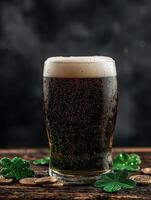 Close up of a glass of dark beer with shamrocks and coins on a wooden table photo