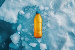 Yellow plastic bottle cooling on ice in arctic environment photo