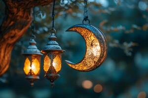 Ornate lanterns and crescent moon hanging from tree branch at night photo