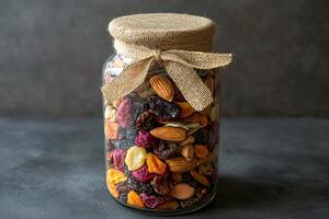 Glass jar filled with healthy dried fruits, nuts and almonds photo
