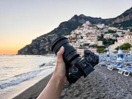 Camera in hand with view over Positano town and beach in Amalfi coast in Italy. photo