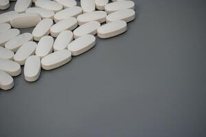 White tablets scattered on a gray surface with neutral lighting photo