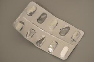 Pill blister pack with missing tablets on gray background photo