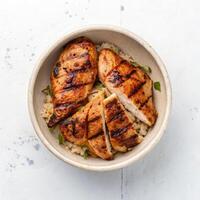 Top View of Grilled Chicken Breast Slices in a Bowl on a White Background photo