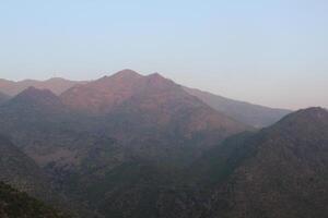 A view of a mountain range with a plane flying over it photo