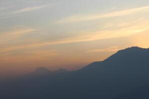 A plane flying over a mountain at sunset photo