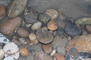 A bunch of rocks and pebbles in a shallow water photo