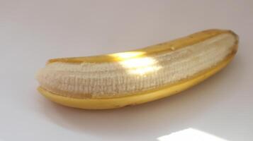 photo of a large banana that is slightly peeled