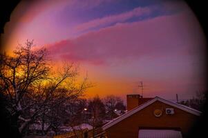 Sunset with a house in front and trees in the back photo