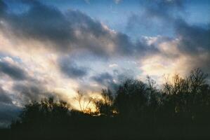 Sunset and clouds over forest create a peaceful setting at dusk photo