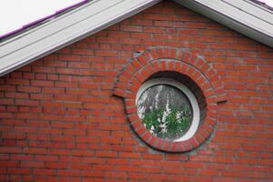 There is a brick wall that features a round window embedded within it photo