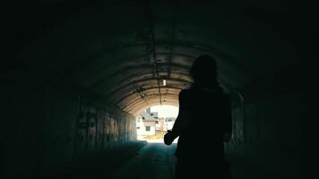 Woman runs to the light at the end of the tunnel. Silhouette of a woman running in an unlit tunnel. video