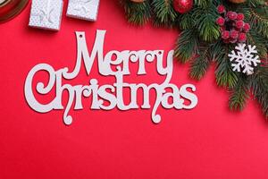 branches of a Christmas tree with cones and toys on a red background with the inscription Merry Christmas photo