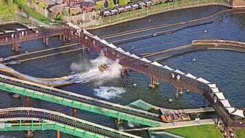 Aerial view of a water ride and pedestrian bridge in a theme park, water attraction with splashing waves and a bridge, seen from above in a park. video