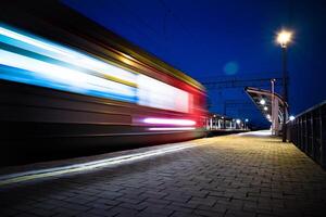Evening arrival of the train on an empty platform. Phto taken with a shutter speed. Rays of light. Blur. Evening railway station. photo