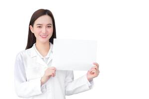 Young professional asian woman doctor who wears medical coat holds and shows white paper to present something in healthcare concept while isolated white background. photo