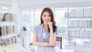 Professional Asian confident working woman who has long hair is standing and arm crossing in work while isolated office background photo