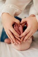 A close up of parents hands forming a heart around their newborns tiny feet, symbolizing love, family, and new beginnings. photo