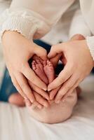 A close up of parents hands forming a heart around their newborns tiny feet, symbolizing love, family, and new beginnings. photo