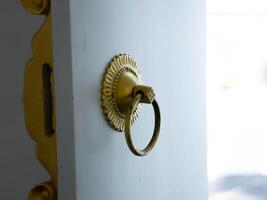 A white front door with a gold colored ring handle as a doorknob. photo