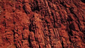 Vivid red rock face with layered formations and intricate fissures, reflecting natural erosion and rugged surfaces ideal for architecture, abstract design, and geological backgrounds. photo