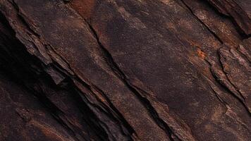 Dark rugged stone face with deep shadows and fine fissures, reflecting the raw beauty of geological formations, perfect for architectural backgrounds, design, and artistic natural patterns. photo
