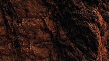 Dark brown rock face with deep crevices and rugged stone formations, representing natural erosion and mineral-rich patterns perfect for architectural and geological background designs. photo