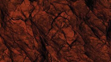 Dark textured rock with deep red hues and fissured surfaces, representing natural geological formations ideal for architecture, abstract backgrounds, and stone design projects. photo