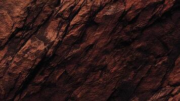 Dark rugged rock face with pronounced fissures and rough sediment patterns, ideal for geological backgrounds, design, and architectural surface projects. photo