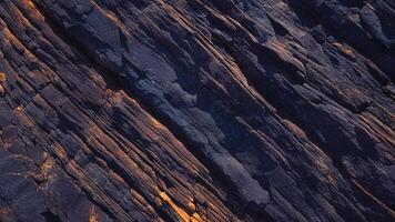 Rough slate rock texture with rust accents and deep fissures, ideal for geology-themed backgrounds, stone designs, and architectural elements with organic patterns photo