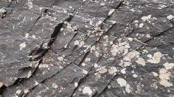 Rough layered slate rock texture with fissured surface details, offering geological design inspiration for stone backgrounds, architectural patterns, and natural outdoor textures photo