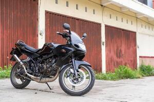 Modern black motorcycle parked in front of a rustic red warehouse, perfect for themes of adventure and modern lifestyle photo