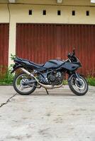 a black motorcycle parked in front of a red building photo