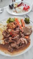 Beef stew with mashed potatoes, vegetables and fried dumplings served with fruit salad in an egyptian sataya resort photo