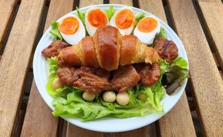 Delicious Croissant with Egg and Meat on Fresh Green Salad Plate photo