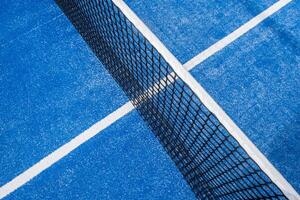 top view of the net of a blue paddle tennis court, textured background for the racket sports concept. photo