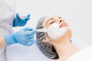 Caucasian adult woman receiving a anti-aging facial mask applied by beautician in spa setting. Facial treatment for glowing skin rejuvenation. Showcasing wellness and tranquility in a beauty setting photo