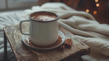 Homemade hot chocolate in a white enamel mug with cinnamon sticks on a wooden tray in a cozy setting photo