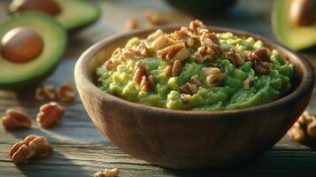 Wooden bowl of creamy guacamole with crunchy walnut pieces, surrounded by fresh avocado photo
