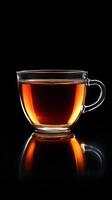 Glass cup filled with hot tea against a black background, transparency mug and rich color photo