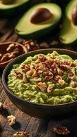 Bowl of creamy guacamole topped with crunchy walnut pieces, fresh avocado and walnut photo